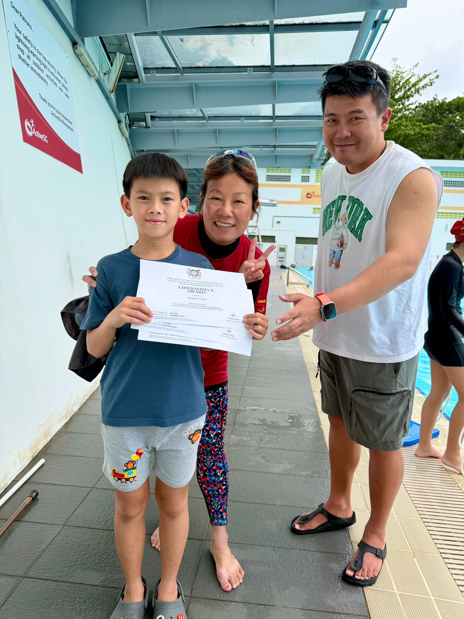 Swim Masters coach with a happy young swimmer giving a thumbs up after a Bukit Panjang swimming lesson